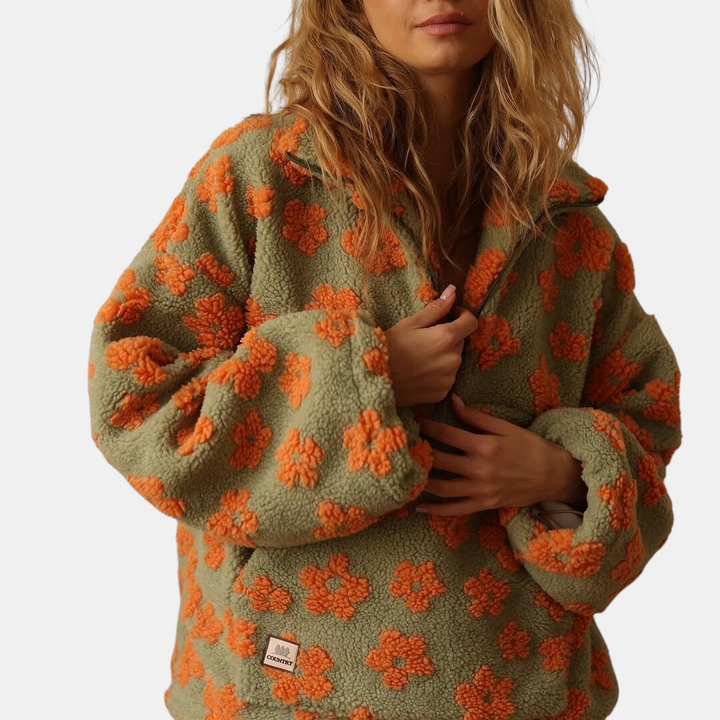 Casaco Margaret Dublin Daisy de fleece sherpa verde com padrão floral laranja, corte oversized e fecho frontal.