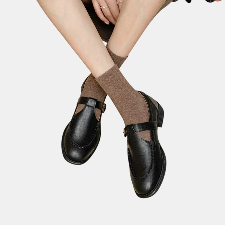 Sapatos retro pretos Margaret Dublin com tira em T, salto médio e meias castanhas, estilo elegante e feminino.