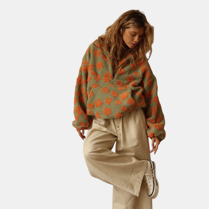 Modelo veste Margaret Dublin Daisy Fleece Warm Bloom verde e laranja com estampa floral boho e ajuste oversized